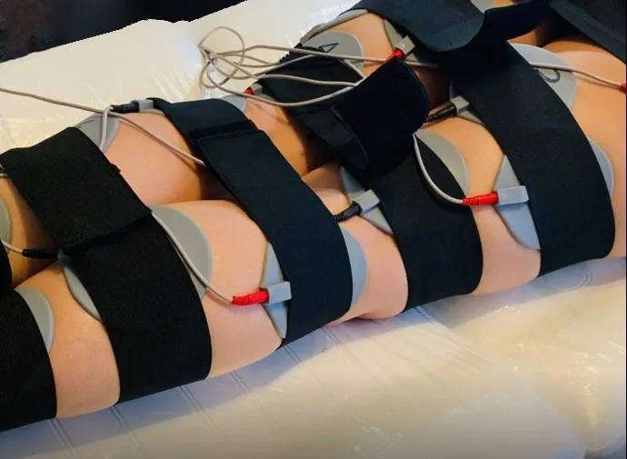 Electrical treatment pads positioned across the thighs and abdomen