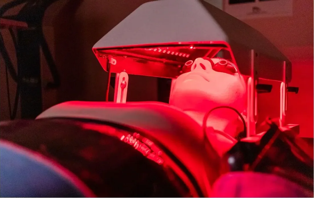 A client lying beneath a red-light treatment dome